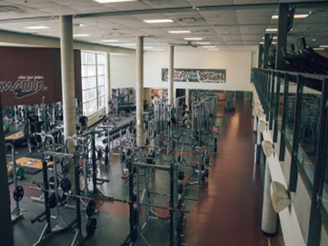 Room with rows of barbell stands and gym equipment