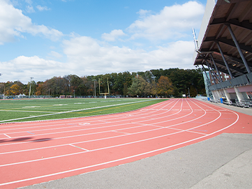 Outdoor field with surrounding track and background trees