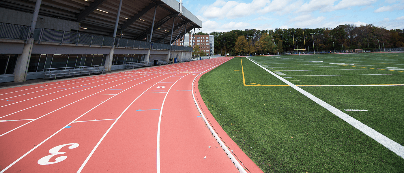 Lush green football field with a running track and recreation center